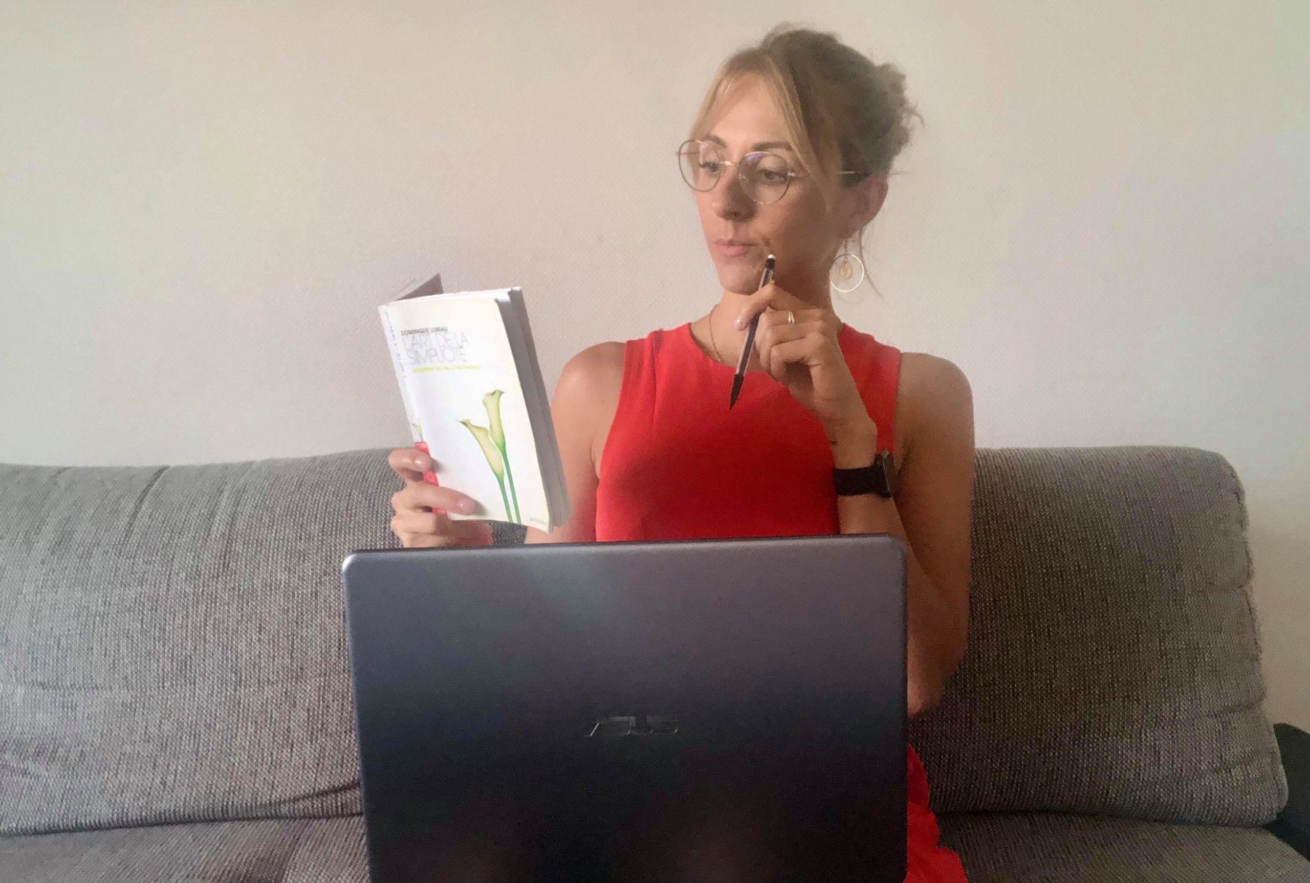 femme blonde avec des lunettes lisant un livre et travaillant sur le pc en même temps