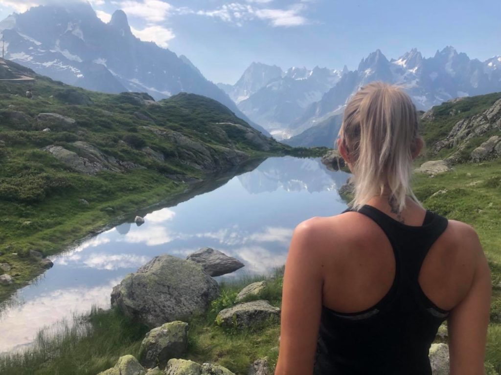 Photo d"une femme qui regarde un magnifique paysage : lac et montagne 