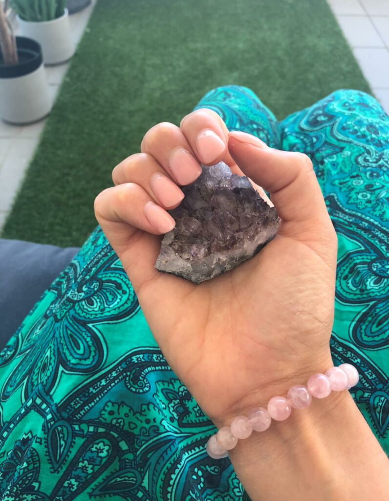 main tenant une pierre naturel améthyste et un bracelet quartz rose 