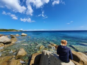 femme assise sur un rocher en face de la mer